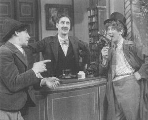 Chico and Groucho engage in some idle banter while watching Harpo eat everything off the hotel reception desk.